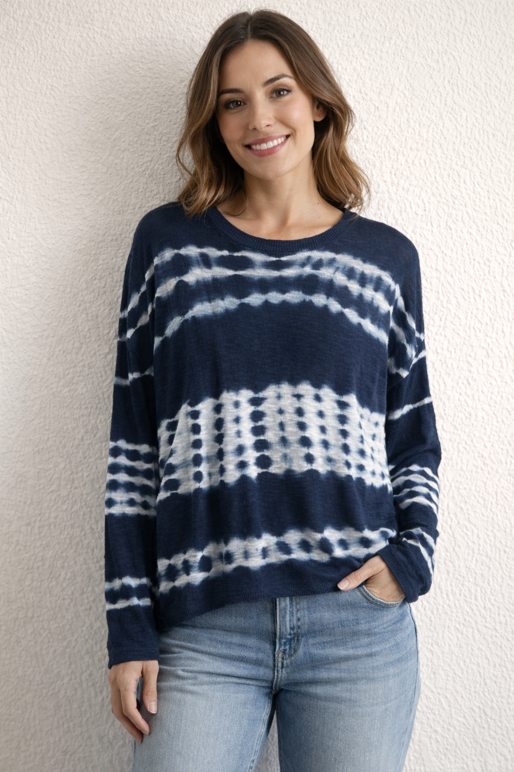 Woman wearing navy and white tie dye lightweight knit long sleeve top paired with denim jeans from Ellen Jane Boutique.
